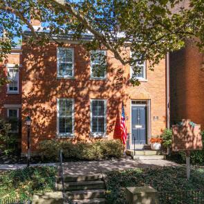 Red-brick historic home with shaded front entrance and flag display.